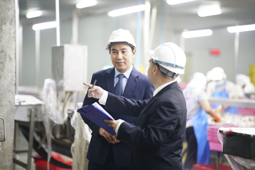 Business meeting in manufacturing facility during daytime with safety gear and focused discussions