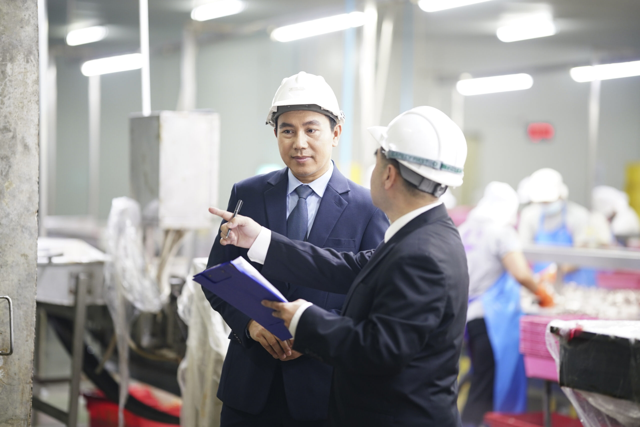 Business meeting in manufacturing facility during daytime with safety gear and focused discussions